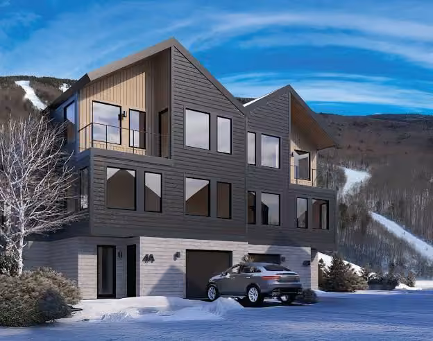 A modern mountain duplex with timber and dark siding below a ski slope